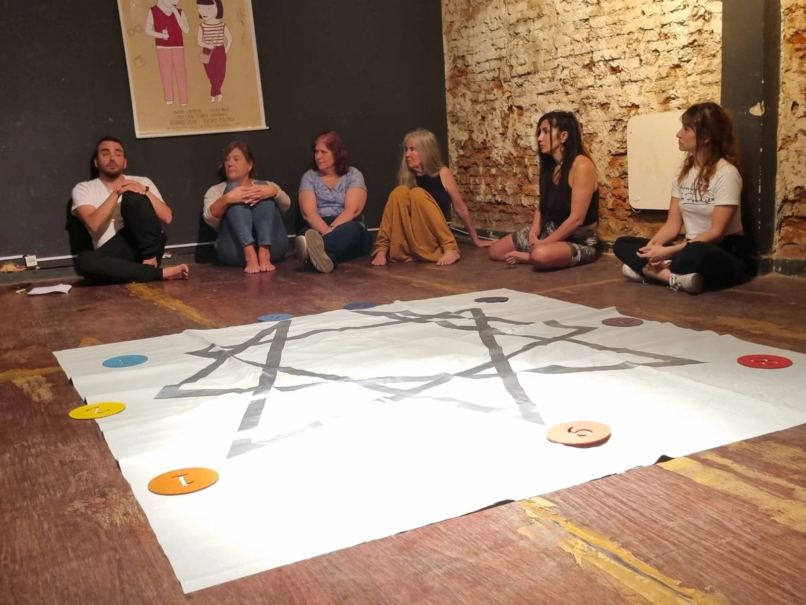 Participantes sentados junto a una lona con el símbolo del Eneagrama