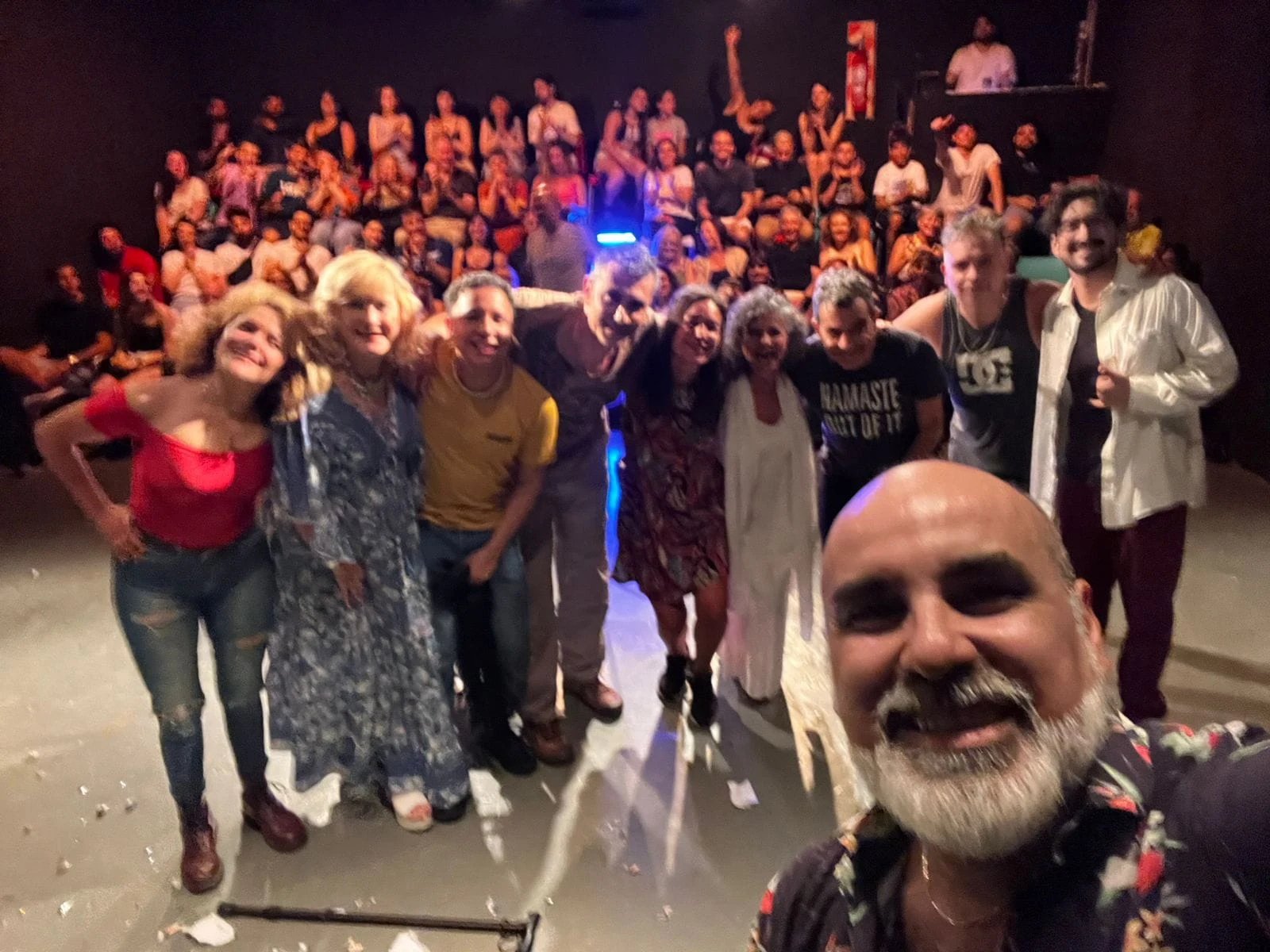 Foto grupal en una sala teatral, con público al fondo